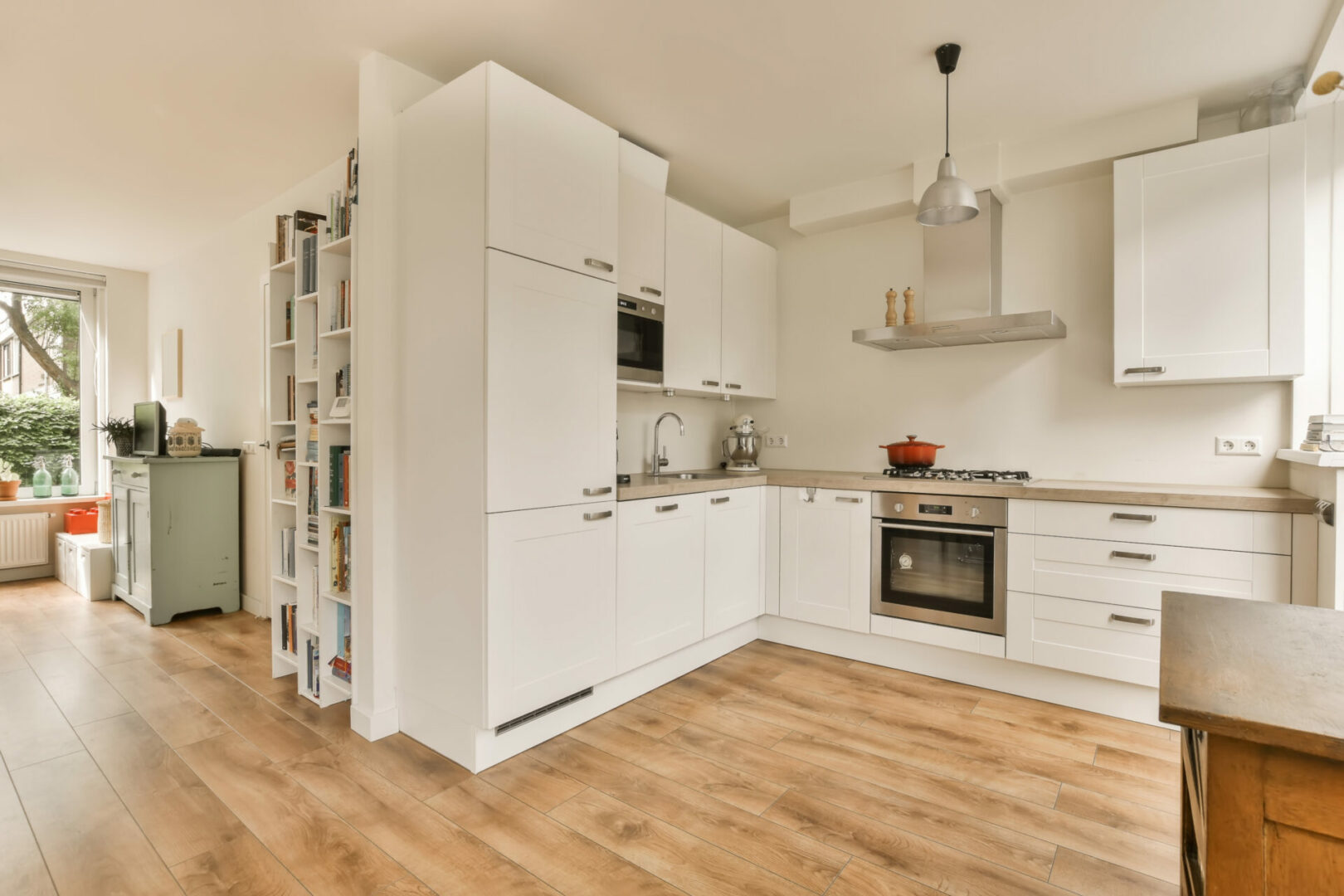 A kitchen with white cabinets and a wooden floor