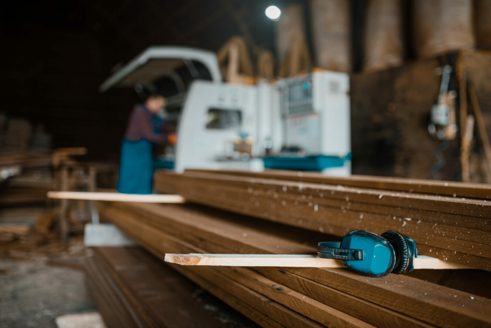 Stack of boards, carpenter at woodworking machine