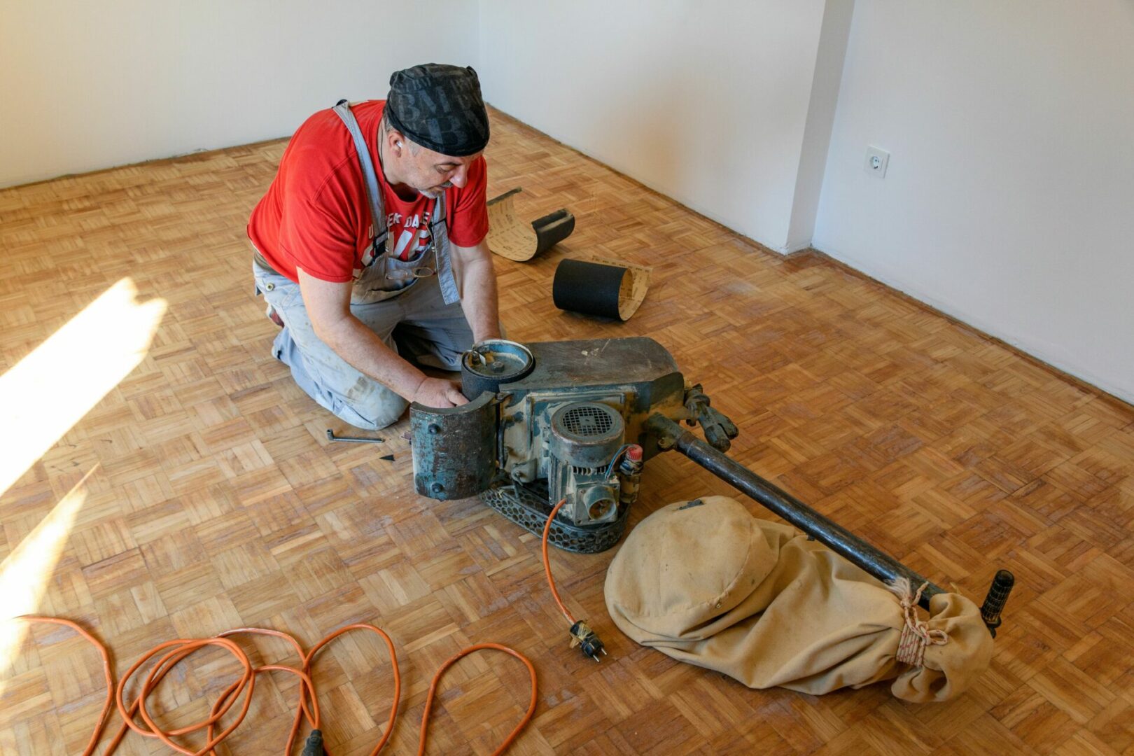 Worker changing sanding paper on a grinding machine for hardwood floor